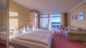 A hotel room with two beds, a sofa, a small table, and a view of the outdoors. - Apartment in Granzow Near the Lake (Mirow)