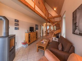 Un espacio habitable amplio con chimenea, escalera de madera y un sofá acogedor.
