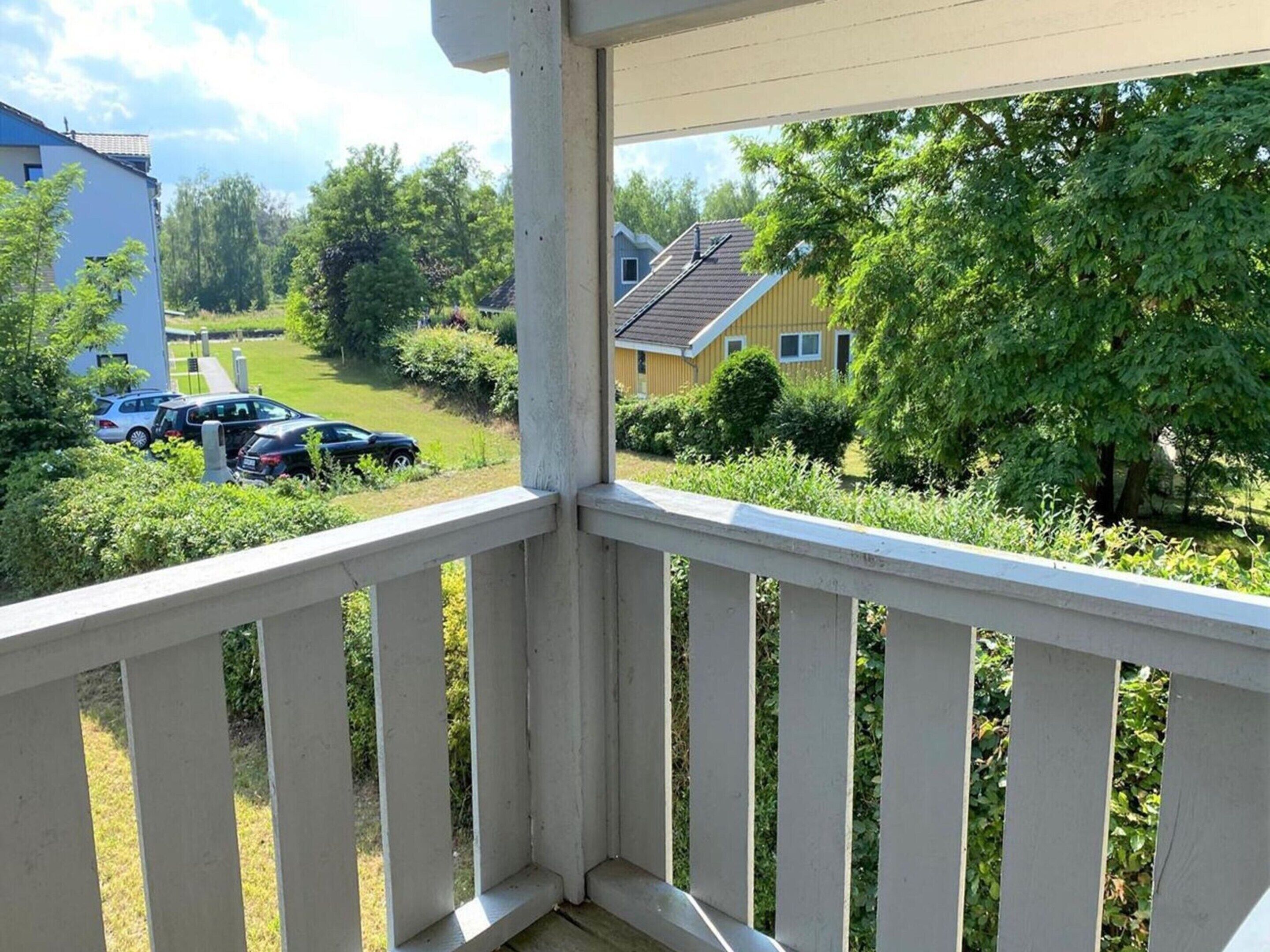 A balcony with a view of a residential area, including houses and parked cars.