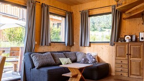 Interior acolhedor de uma cabana com um sofá de madeira, uma mesinha e um armário.