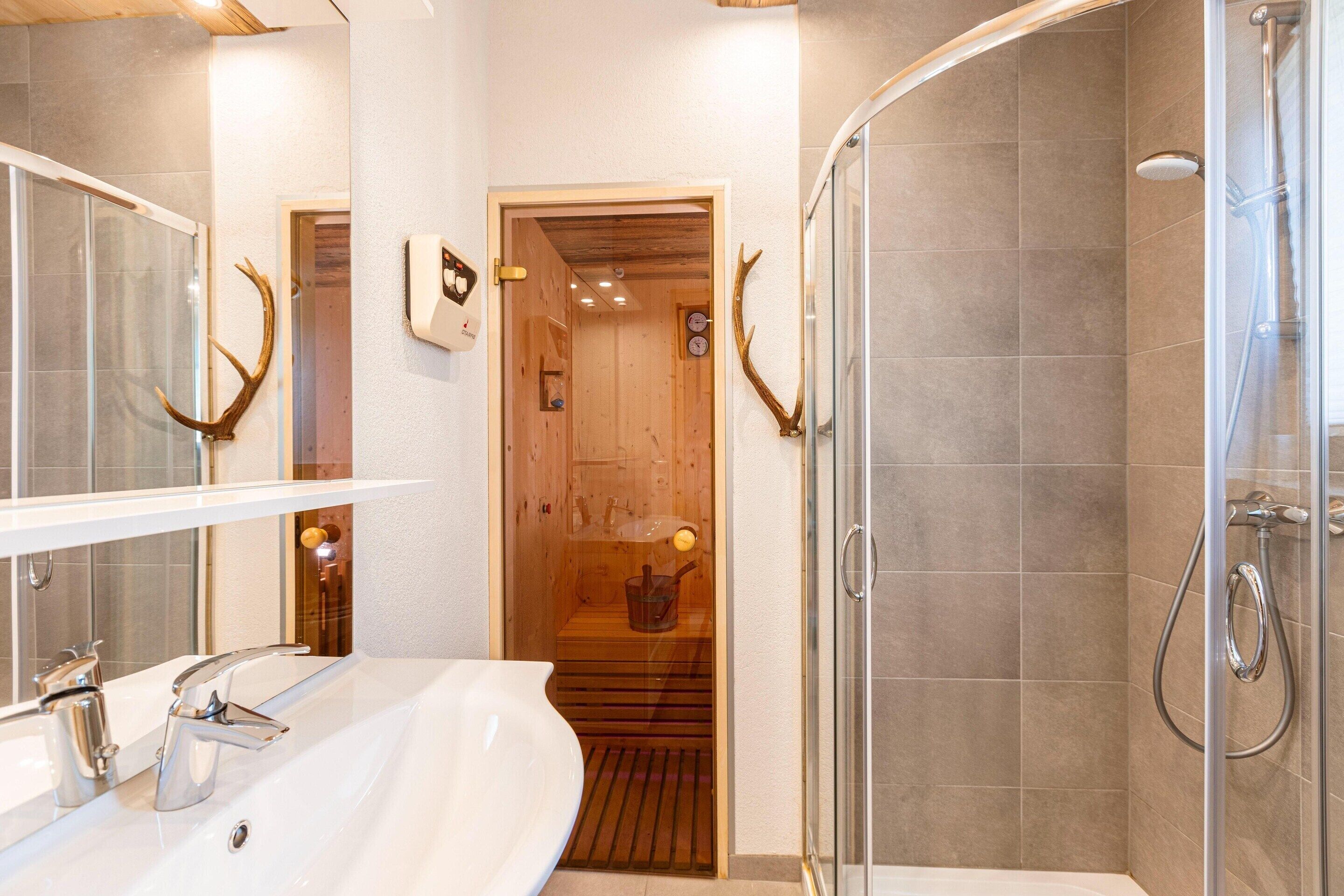 Une salle de bain dotée d’un grand miroir, de deux lavabos, d’une douche et d’éléments décoratifs en bois.