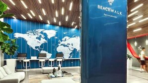 Un hall d’entrée moderne avec une carte du monde au mur, un comptoir de réception bleu et un escalier.