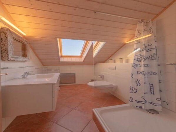 A bathroom with a skylight, a bathtub, and a shower curtain with a pattern.