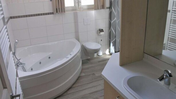 Une salle de bain moderne avec une baignoire sur pieds, des toilettes et un lavabo.