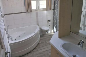 A modern bathroom with a freestanding bathtub, a toilet, and a sink. - Ferienhaus im Ferienpark Mirow (Mirow)