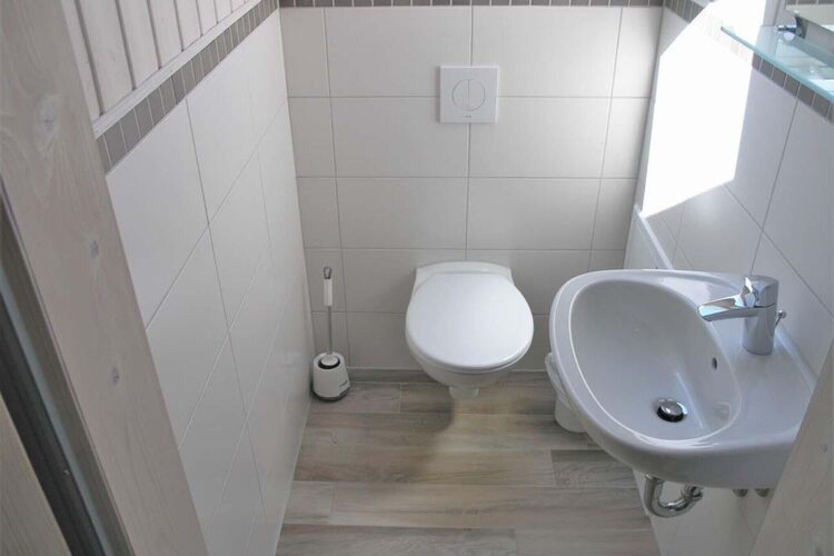 Ein kleines, sauberes Badezimmer mit Toilette, Waschbecken und einem Mop.