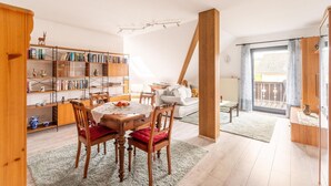 Een gezellige woonkamer met een eethoek, houten boekenkasten en een groot raam.