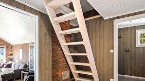 A modern loft bedroom with a wooden staircase, a brick fireplace, and a large window. - 4 Star Holiday Home in Naustbukta (Nærøysund)