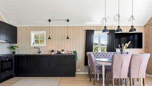 A modern kitchen with a black island, pendant lights, and a dining area with a round table and chairs. - 4 Star Holiday Home in Naustbukta (Nærøysund)