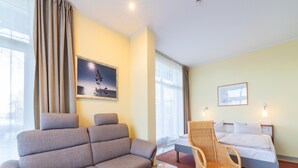 Ein Hotelzimmer mit einer Couch, einem Sessel, einem Bett und einem Holztisch.