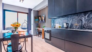 Eine moderne Küche mit großem Fernseher, Holzboden und einer Essecke mit Tisch und Stühlen.
