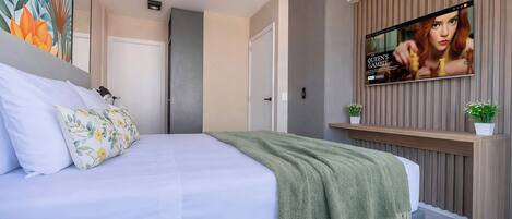 A modern bedroom with a bed, a TV mounted on the wall, and a door.