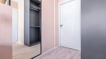 A hallway with a wooden floor, a grey wardrobe, and a white door.