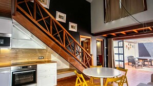Una cocina moderna con horno empotrado, armarios blancos y una escalera de madera.