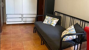 Una habitación pequeña con una cama, un armario y un cuadro en la pared.