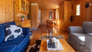 A cozy cabin interior with a wooden interior, a dining area, and a living room with a blue sofa and a grey sofa. - Chalet Verrel Near Aletsch Ski Gondolas (Fiesch)