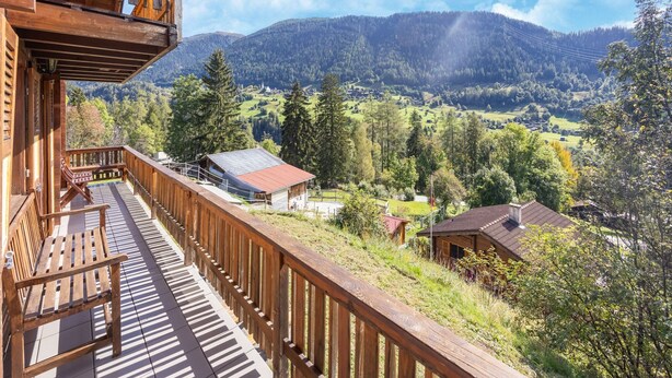 A wooden balcony with a view of a mountainous landscape and a small building with a red roof. - Chalet Verrel Near Aletsch Ski Gondolas (Fiesch)