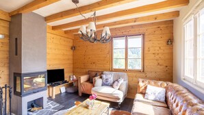 A cozy log cabin interior with a fireplace, leather sofa, and wooden beams. - Chalet Verrel Near Aletsch Ski Gondolas (Fiesch)