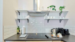 A modern kitchen with white cabinets, a black countertop, a built-in stove, and a coffee machine. - Grand Place Central Gem 4

 (Bruxelles)