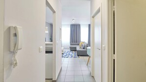 A hallway leading to a living area with a sofa, a patterned rug, and a telephone on the wall. - Grand Place Central Gem 4

 (Bruxelles)