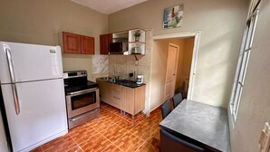 A compact kitchen with a refrigerator, stove, oven, and a small dining area.