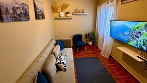 A living room with a sofa, a chair, a TV, and a ceiling fan.