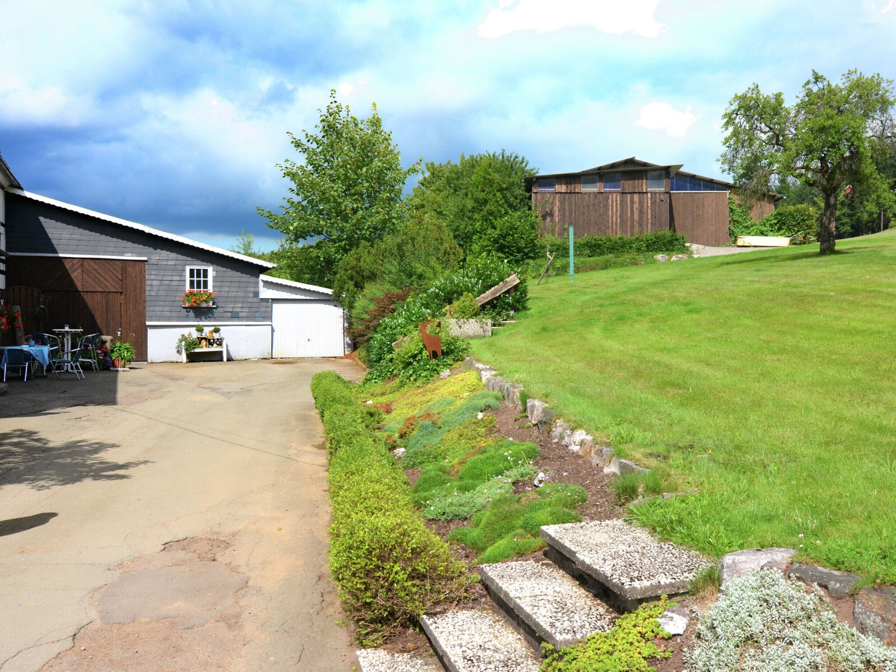 A residential property with a garage, a patio with outdoor furniture, and a well-maintained lawn.