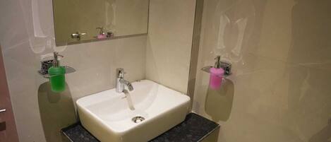 Un baño con un lavabo blanco, un espejo y dos dispensadores de jabón.