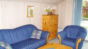 Ein Zimmer mit zwei blauen Sofas, einem Holzkasten und einem kleinen Tisch mit einer Fernbedienung.