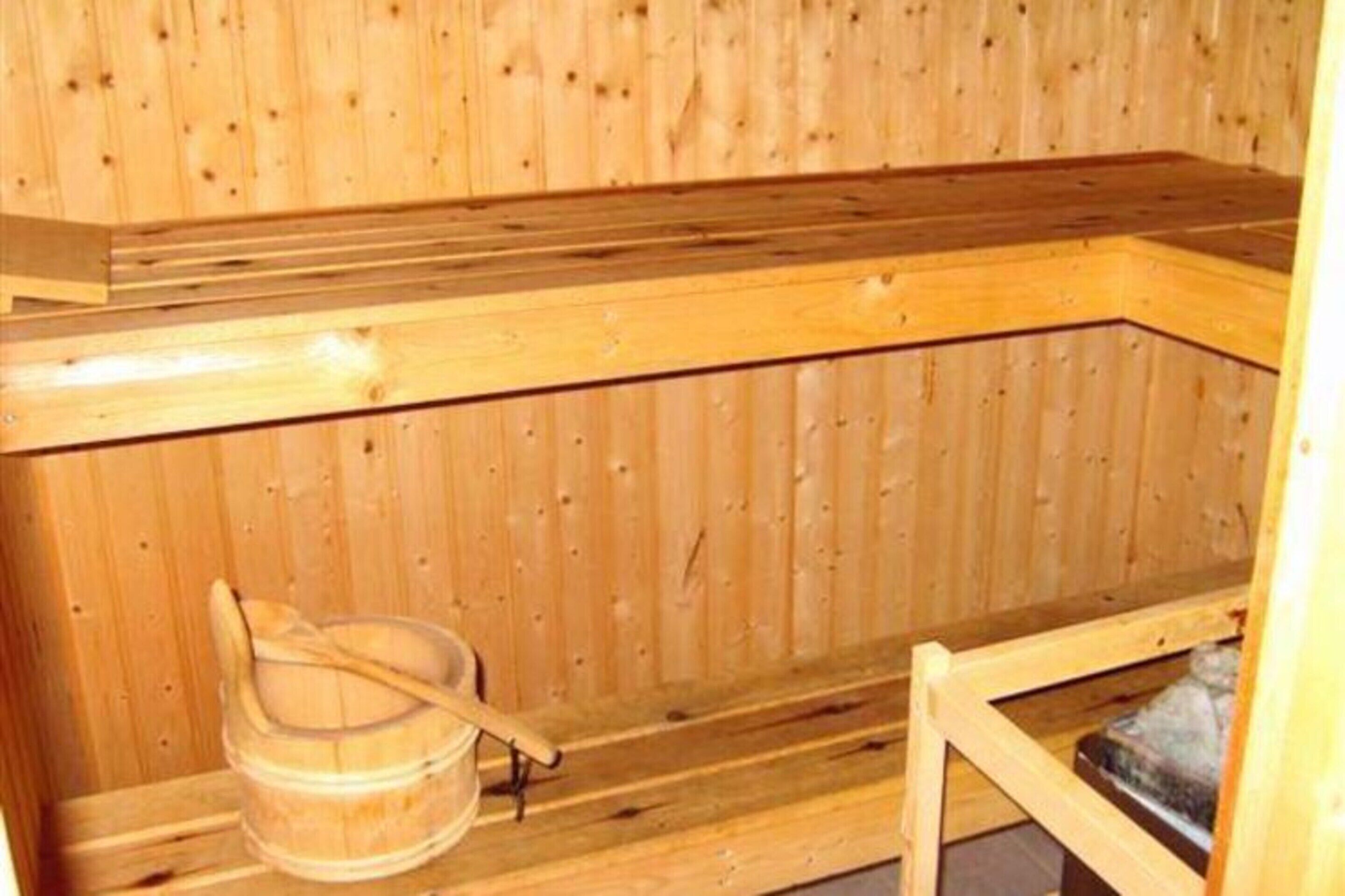 A wooden sauna with a bench and a wooden bucket.