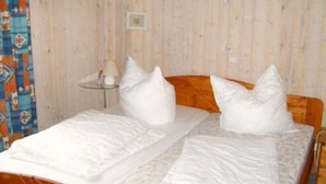 Ein Einzelbett mit Holz-Kopfteil, weißen Bettwäsche und zwei weißen Kissen.