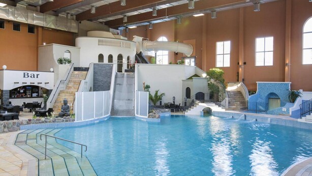 Ein Hallenbad mit Bar, Wasserrutsche und einer Sitzecke mit Buddha-Statue.