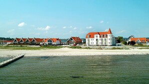 Ett hotell vid kusten med flera byggnader, en sandstrand och en brygga som sträcker sig ut i vattnet.