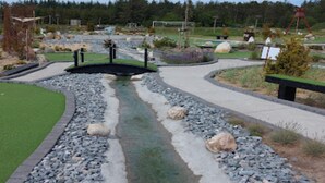 Een aangelegde tuin met een kleine waterpartij, paden en bankjes.