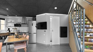 Een moderne keuken met een eethoek, een ingebouwde oven en een trap naar een hoger gelegen verdieping.