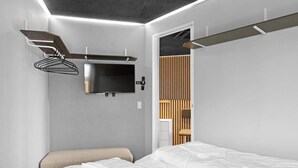 Een moderne slaapkamer met een bed, een aan de muur bevestigde televisie en een wandpaneel van hout.