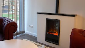 A modern living room with a fireplace, a sofa, and a large window. - Chalet in Wendorf (Kuhlen-Wendorf)