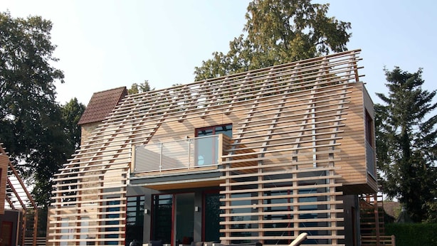 A modern house with a sloped roof, large windows, and a wooden deck. - Chalet in Wendorf (Kuhlen-Wendorf)