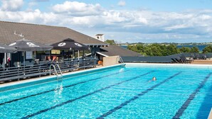 Ein Schwimmbecken mit klarem, blauem Wasser, Liegestühlen und Sonnenschirmen.