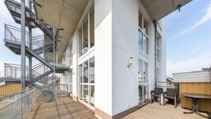 A deck with a metal staircase leading to an upper level, large windows, and a wooden deck. - Ferienwohnung im Ferienpark Mueritz (Rechlin)