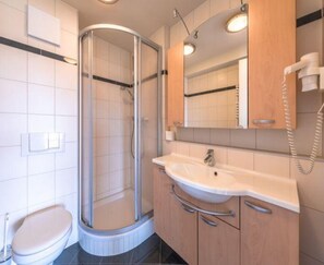 A modern bathroom with a glass-enclosed shower, a white sink, and wooden cabinets. - Ferienwohnung im Ferienpark Mueritz (Rechlin)
