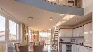 A spacious, modern kitchen with a dining area, large windows, and a staircase leading to an upper level. - Ferienwohnung im Ferienpark Mueritz (Rechlin)