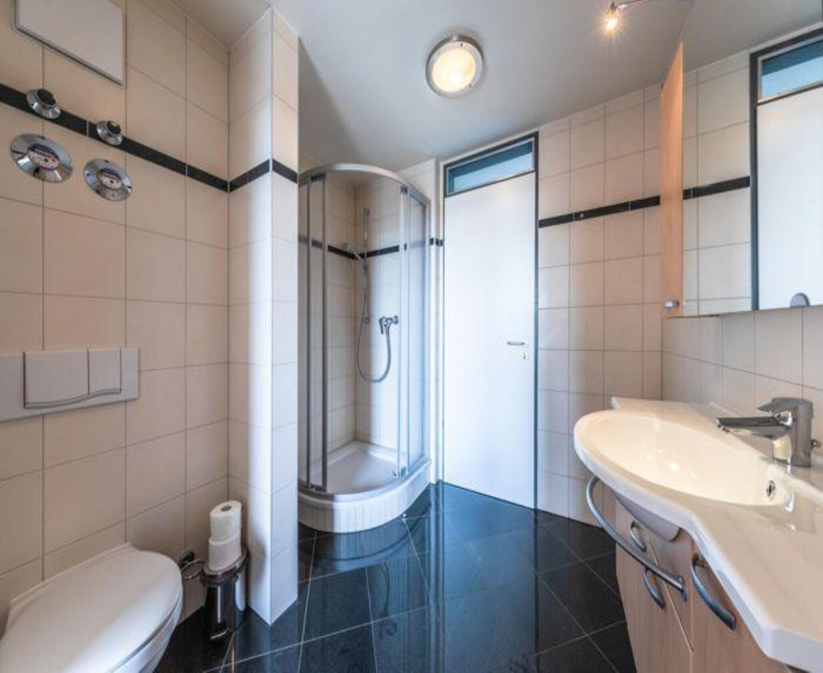 A modern bathroom with a toilet, a shower, and a sink.