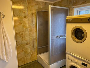 A bathroom with a marble wall, a shower enclosure, a washing machine, and a towel rack. - 6 Person Holiday Home in Storslett (Nordreisa)