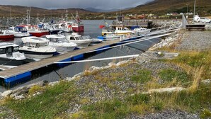 A marina with several boats docked, a wooden pier, and a mountainous backdrop. - 6 Person Holiday Home in Storslett (Nordreisa)