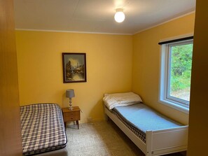 A small, single-bed room with a window, a bedside table with a lamp, and a painting on the wall. - 6 Person Holiday Home in Storslett (Nordreisa)