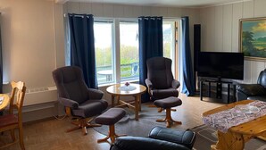 A living room with two armchairs, a sofa, a coffee table, a TV, and a painting on the wall. - 6 Person Holiday Home in Storslett (Nordreisa)