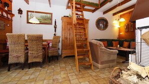 A cozy living room with a wooden ladder, wicker chairs, a sofa, and a tiled floor. - Ferienhaus in Wieda mit Garten (Walkenried)