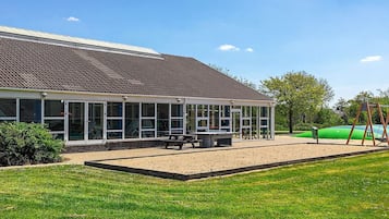 A building with a covered patio area, a bench, and a swing set.