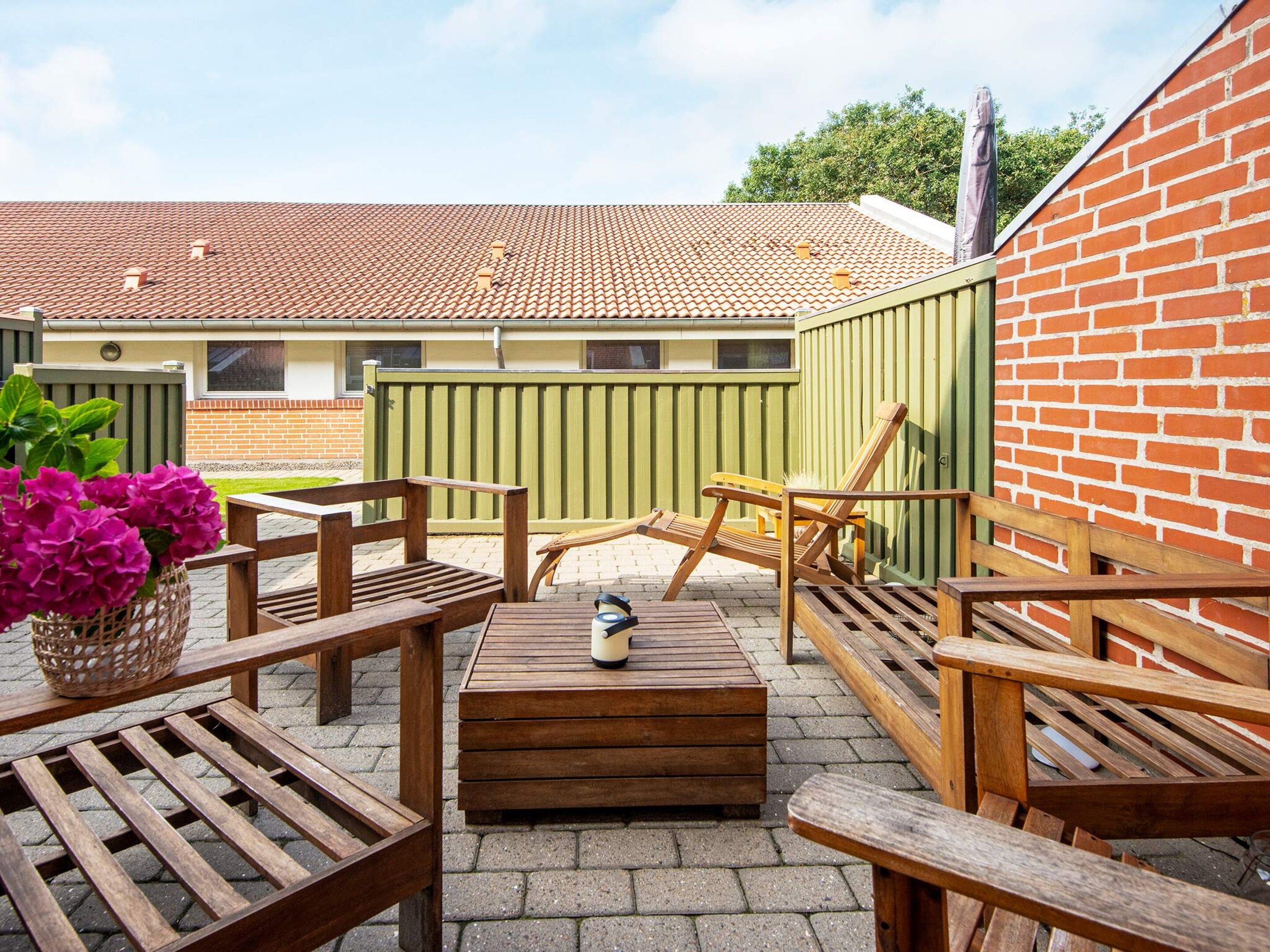 A patio area with wooden furniture, a table, and a bench.